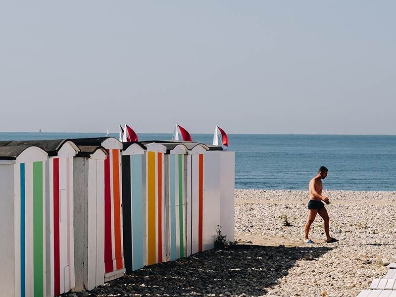 Cabanes de plage colorées alignées sur les galets de la plage du Havre